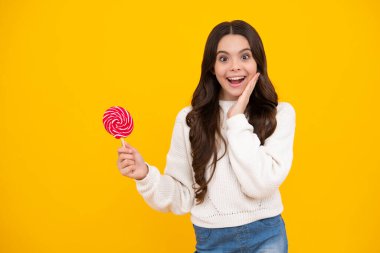Genç kız sarı arka planda lolipop karamel tutuyor, şekerci dükkanı. Tatlılı ergen enayiler. Mutlu yüz, pozitif ve gülümseyen genç kız duyguları