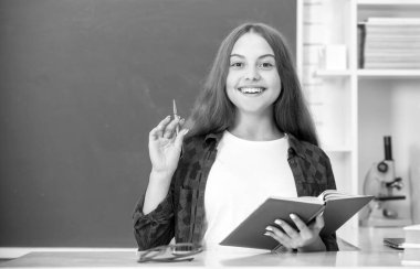 Okula dönüyorum. Genç kız çalışmaya hazır. Çocuk ödevlerini kitapla yapıyor. Genç bir öğrenci. Modern eğitim. Lisede. Kitapçığı olan liseli kız. kopyalama alanı. Neşeli çocuk not defterine not alıyor..