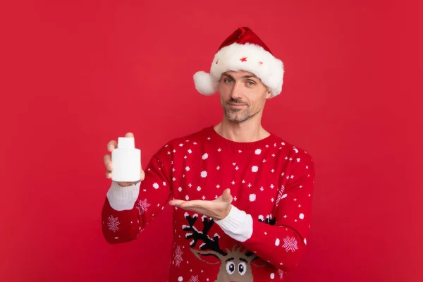 Чоловік Різдвяному Светрі Капелюсі Тримає Пляшку Ліків Кольоровому Фоні Санта — стокове фото