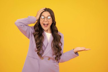 Wow, its unbelievable. Shocked teenager child pointing aside at copy space. Teen girl pointing with two hands and fingers to the side. Amazed teen girl. Excited expression, cheerful and glad