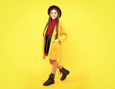 Sarı arka planda izole edilmiş rahat moda sonbahar ceketi giyen neşeli genç kız çocuğu. Mutlu ergen portresi. Kopyalama alanı oluştur