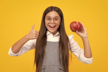 Teenager child girl biting tasty green apple. Happy girl face, positive and smiling emotions