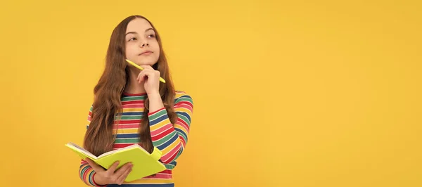 stock image Thoughtful girl child think holding school copybook and pen yellow background, thinking. Banner of schoolgirl student. School child pupil portrait with copy space