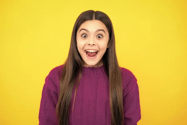 Excited kids face. Amazed expression, cheerful and glad. Excited teenager girl opening mouth in excitement, believe big sale or promo on yellow studio background, copy space