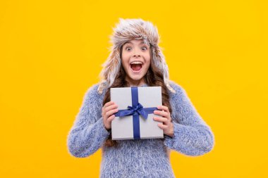 Kara Cuma indirimi. Kış alışverişi. Doğum günü hediyesi kutusu. Noel sezonu. Hayret bir çocuk şapkadan alışveriş yapıyor. Boks günü. Sarı arka planda örgü giyen genç bir kız. çocuk hediyesi.