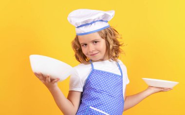 Mutfak tabağıyla komik aşçı çocuk, stüdyo portresi. Aşçı çocuk, stüdyo resmi. Çocuklar yemek yapıyor. Önlüklü ve aşçı şapkalı çocuk.