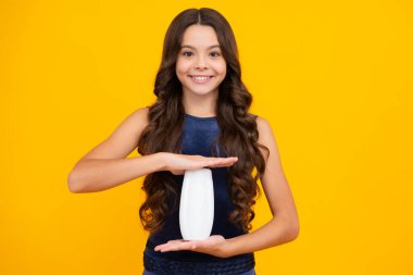 Şampuan kremi kullanan bir çocuk. Günlük kozmetik bakım. 12, 13, 14 yaşlarındaki ergen çocuğun elinde saç ve cilt bakımı şişesi var. Güzellik sağlığı ve kozmetik ürünleri. Mutlu kız yüzü, pozitif ve gülümseyen duygular
