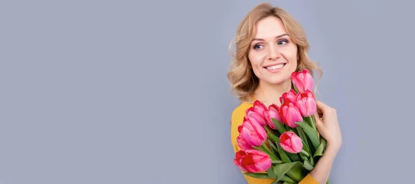 positive woman with tulips on grey background. Woman isolated face portrait, banner with mock up copy space