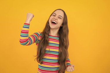 Kazanan jest yapan genç çocuğun stüdyo portresi. Cocuk sevinci, evet zafer sampiyonu jesti, yumruk pompasi. Heyecanlı bir yüz, neşeli genç bir kız.