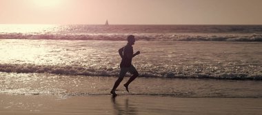 Koşan ve zıplayan adam, fotokopi alanı olan pankart. Sahilde koşan sağlıklı bir adam. Enerjik bir yaz. Koşucu özgürlüğü hisseder. Acele et.