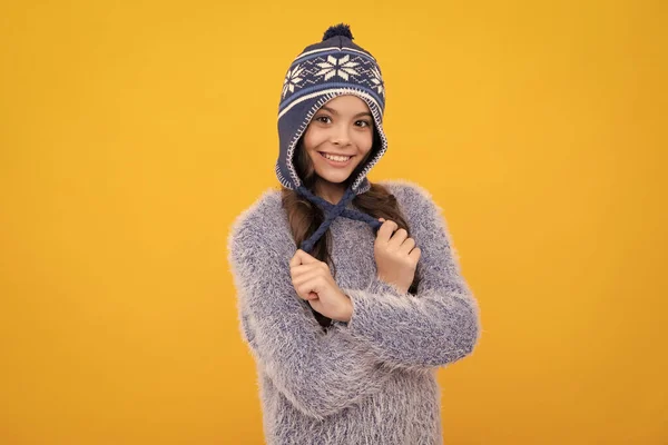 Winter hat. Cold season concept. Winter fashion accessory for children. Teen girl wearing warm knitted hat. Happy face, positive and smiling emotions of teenager girl