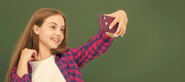 vlogger with cellphone in classroom. making video blog on smartphone. teen girl blogging on phone. Banner of school girl student. Schoolgirl pupil portrait with copy space
