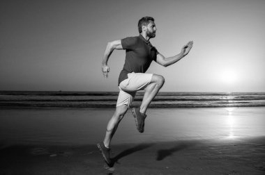 Günbatımı plajında koşan atletik erkek koşucu, sporcu..