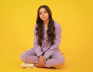 Uzun boylu, neşeli, neşeli bir genç kız. Keyfi yerinde ve sarı arka planda izole edilmiş günlük kıyafetlerle poz veriyor.