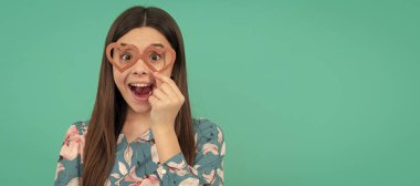 Eğlenceli olsun. Komik çocuk kalp şeklinde gözlük takıyor. Şaşırmış kız. Sevgililer günü eğlencesi. Partideki komik genç çocuk, afiş başlığı fotokopi alanı