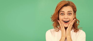 İzole edilmiş yüz portresi, fotokopi alanı olan pankart. Şaşırmış kızıl saçlı, kıvırcık saçlı ve sağlıklı tenli, mavi arka planda, sürpriz.