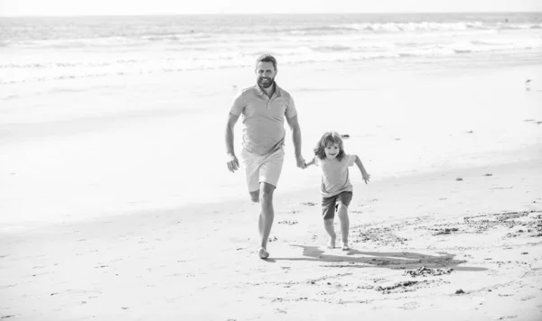 fathers or family day. daddy with kid boy on summer day. dad and child having fun outdoors. childhood and parenting. happy father and son running on summer beach. family travel weekend and vacation.