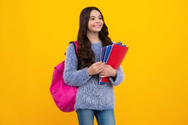 Back to school. Teenager schoolgirl hold book and copybook ready to learn. School children on isolated yellow studio background. Happy teenager, positive and smiling emotions of teen girl