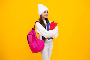 Sonbahar okulu tatili. Okula dönelim. Sonbahar kıyafetleri içinde sarı izole edilmiş stüdyo arka planında genç bir kız öğrenci.