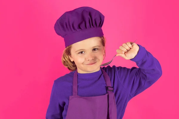 Funny kid chef cook with spoon. Kid chef cook, studio portrait. Children cooking. Kid boy with apron and chef hat