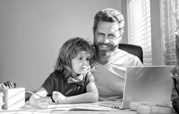 bearded dad or school private tutor teaching boy son with modern laptop, homeschooling.