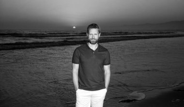 Güneşin batışındaki sahilde neşeli bir adam, tatil.