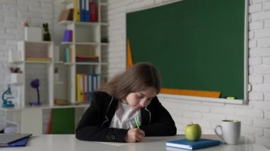 Sınıfta ve çocuklukta kalemle yazmayı düşünen çocuk..