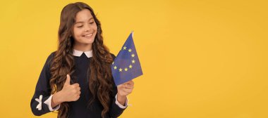 happy teen girl hold european union flag yellow background show thumb up, schengen. Horizontal poster of isolated child face, banner header, copy space