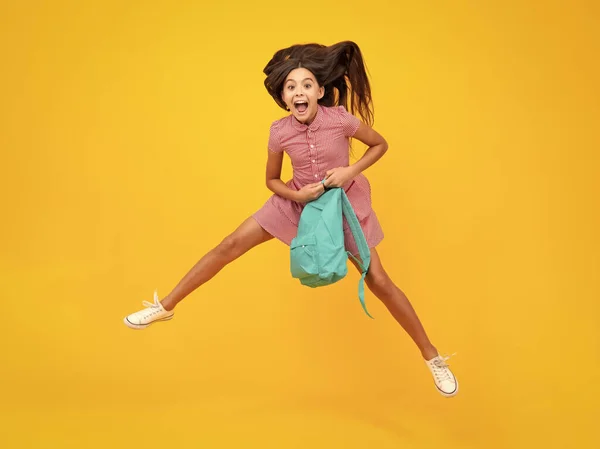 Amazed teen girl. School teen girl in with backpack. Teenager student on isolated background. Kids learning, education, studying and knowledge. Run and jump. Excited expression, cheerful and glad