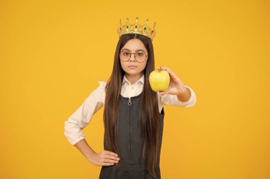 Kraliçe tacındaki genç çocuk sarı arka planda elma tutuyor. Tacın içindeki prenses kız. Genç kız diyabet takıyor.