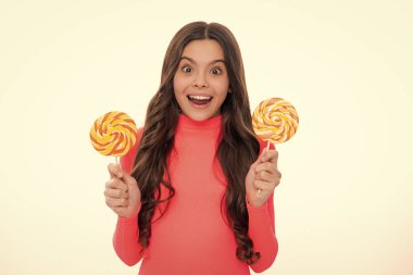 Genç kız beyaz arka planda lolipop karamel tutuyor, şekerci dükkanında. Tatlılı ergen enayiler. Mutlu kız yüzü, pozitif ve gülümseyen duygular
