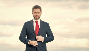cheerful businessman in businesslike suit on sky background.