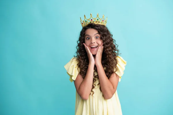 Little queen wearing golden crown. Teenage girl princess holding crown tiara. Prom party, childhood concept. Happy teenager, positive and smiling emotions of teen girl