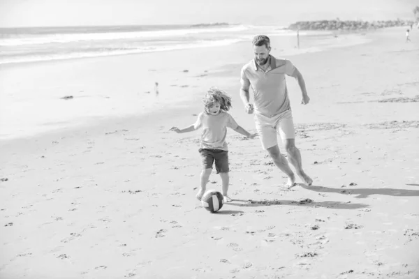 happy father and son play football on summer beach with ball, friendship.