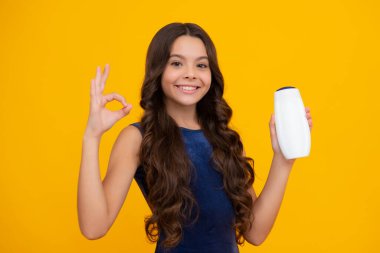 Şampuan kremi kullanan bir çocuk. Günlük kozmetik bakım. Gençlerin elinde saç ve cilt bakımı şişesi var. Güzellik sağlığı ve kozmetik ürünleri. Mutlu kız yüzü, pozitif ve gülümseyen duygular