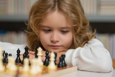 Erkek ve satranç, yakın plan, erken gelişim portresi. Satrancı düşünen çocuk. Erken gelişen çocuklar. Çocuk evde satranç oynuyor. Portre yakın, komik surat.