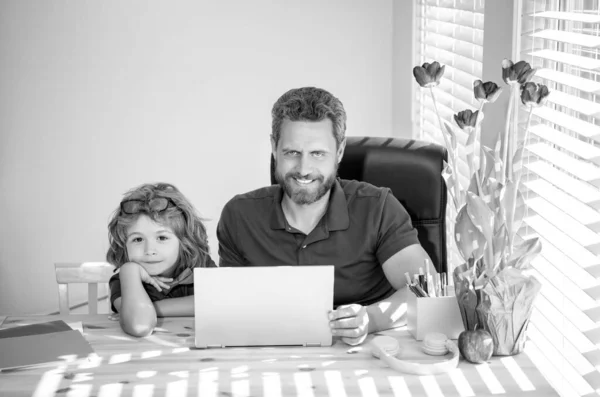 bearded dad or school private tutor teaching boy son with modern laptop, education.