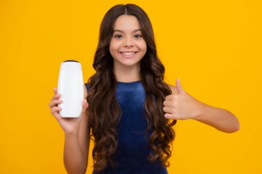 Şampuan kremi kullanan bir çocuk. Günlük kozmetik bakım. Gençlerin elinde saç ve cilt bakımı şişesi var. Güzellik sağlığı ve kozmetik ürünleri. Mutlu kız yüzü, pozitif ve gülümseyen duygular