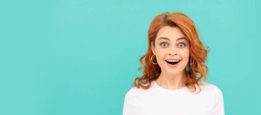 Şaşırmış kızıl saçlı kadın mavi arka planda kırmızı kalbi tutuyor. İzole edilmiş yüz portresi, kopyalama alanı olan pankart