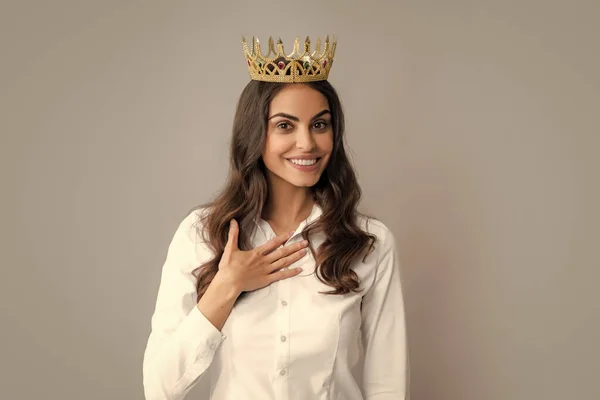 Young lovely woman in crown on gray background. Girl with queen crown celebrating win. Winner concept