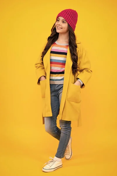 Autumn clothes. Full length of cheerful teenager child girl wearing comfy trendy fashion clothes, isolated over yellow background. Happy teenager, positive and smiling emotions of teen girl