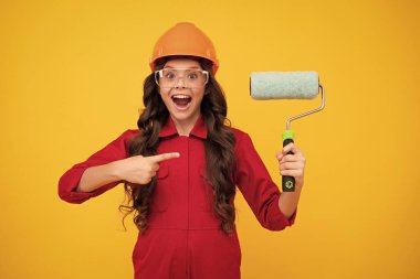 Kasklı, fırçalı çocuk ressamı. Kasklı çocuk. İnşaat alanında boyacı çocuk. Yenileme ve onarım. Genç kızın mutlu gülümseyen duyguları