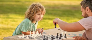 Baba ve oğlu açık havada satranç oynuyor, afiş afişi ve fotokopi alanı, stratejik ve taktik. Özel ders. Baba ve çocuk mantık oyunu oynuyorlar. Baba oğul dışarıda satranç oynuyor..