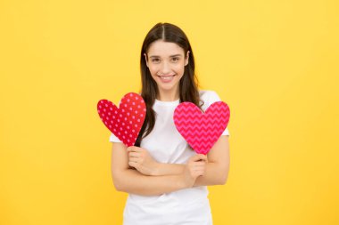 Güzel, harika bir kadın, kağıttan kalp şeklinde, sarı arka planda izole edilmiş rüya gibi. Aşk konsepti