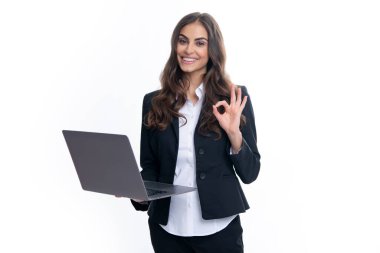 Gri arka planda izole edilmiş dizüstü bilgisayar kullanan genç iş kadınının portresi. Takım elbiseli iş kadınları dizüstü bilgisayardaki bir şeyi heyecanlandırdı. Not defteri tutan iş kadınının portresi