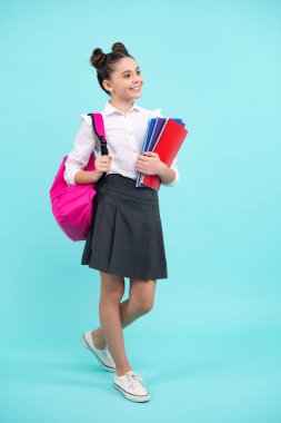 Schoolchild, teenage student girl hold book on blue isolated studio background. School and education concept. Back to school. Happy teenager, positive and smiling emotions of teen girl