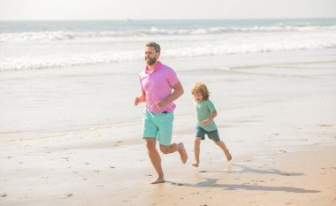 Baba ve çocuk yaz günü. Baba ve çocuk dışarıda eğleniyorlar. Çocukluk ve ebeveynlik. Baba oğul yaz plajında koşuyor. Aile seyahati ve tatil. babalar ya da aile günü.