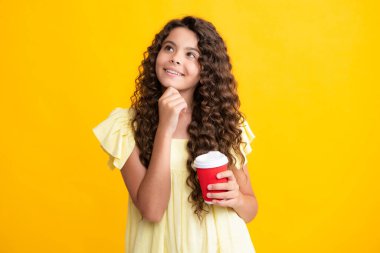 Sarı stüdyo arka planında kahve ya da çay fincanı olan çocuk. İçecek servisi yapan ergen bir kız. Mutlu ergen portresi. Gülümseyen kız