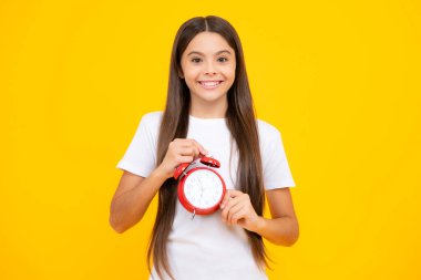 Öğrenci kız saati sarı arka planda izole edilmiş. Okula gitme vakti. Alarmlı saati olan genç bir çocuk, geç uyanmış. Mutlu ergen portresi. Gülümseyen kız