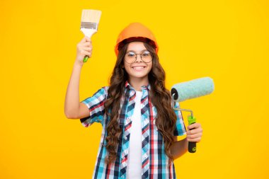 İnşaat, inşaat ve meslek. Sarı arka planda boya silindirli koruyucu başlıklı kız.